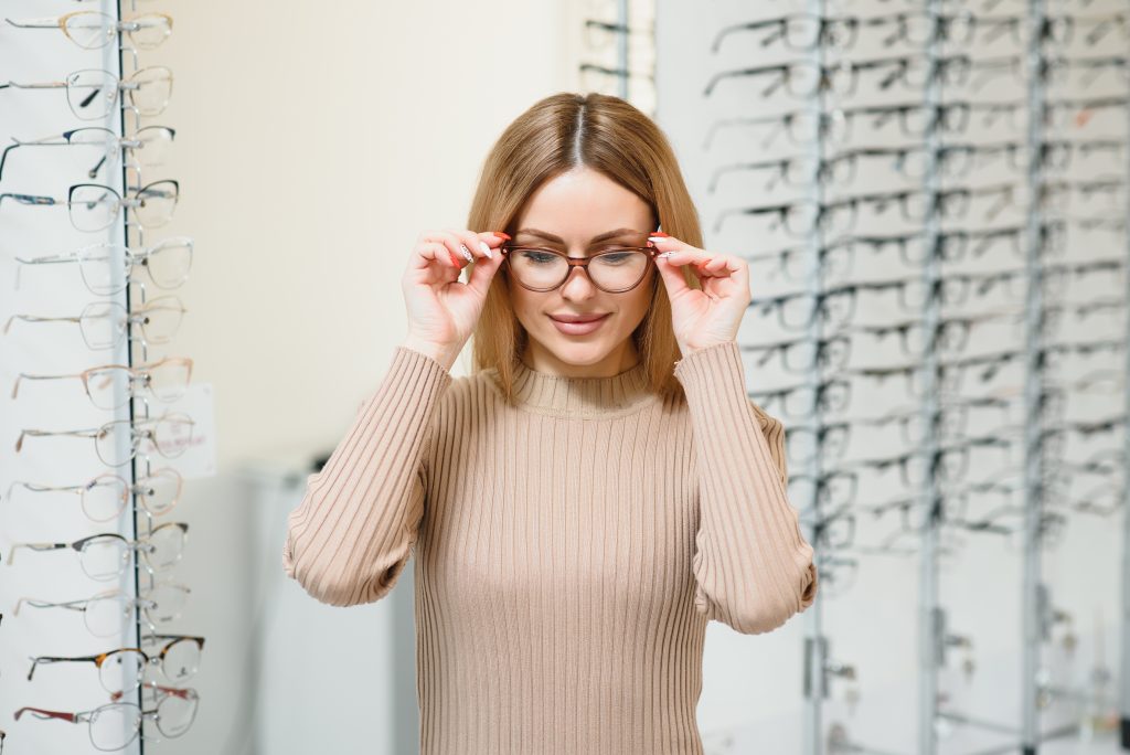 portrait of beautiful young woman trying new glasses in optician store - consurio AG