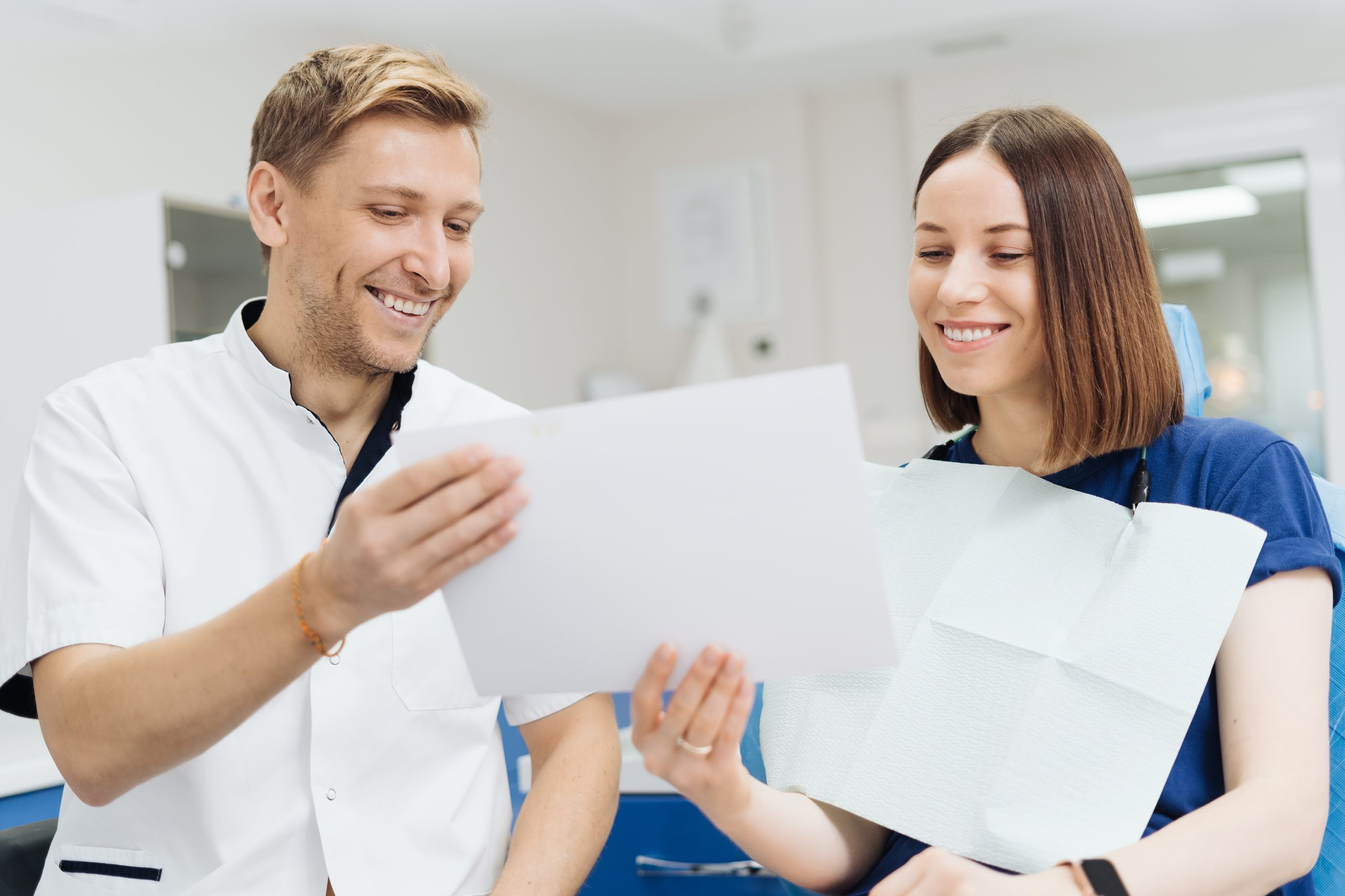 male-professional-dentist-with-gloves-mask-holding-papers-photo-show-what-treatment-will-look-like-patient-s-teeth